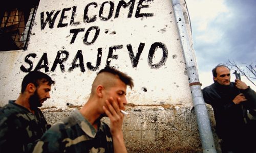 Bosnian soldiers smoke and take a break on the frontline next to a sign that says 'welcome to Sarajevo' in Sarajevo, Bosnia, in the fall of 1994.  Trench warfare was fought all around the city of Sarajevo.